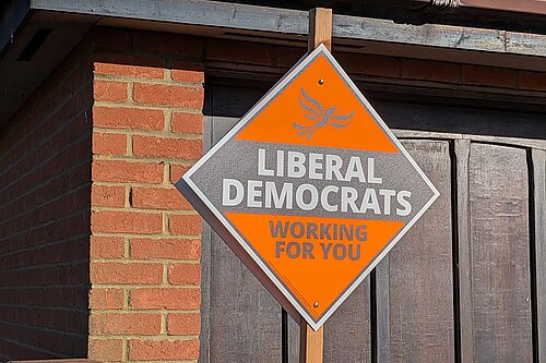 A orange, diamond shaped poster reading "Liberal Democrats" and "Working for you"