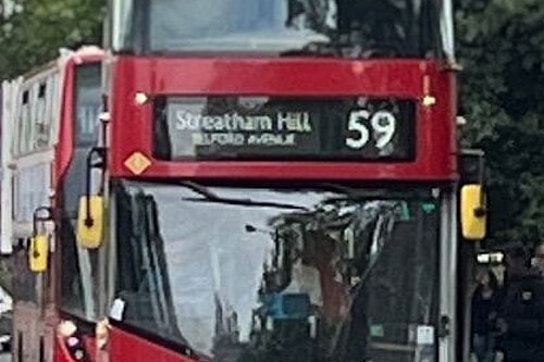 A red double decker bus picking up passengers