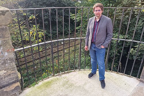 Cllr Jack Caldwell standing in front of railings and the railway line