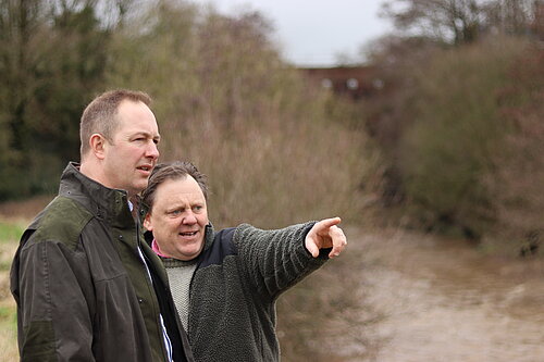 Richard Foord talking to a local resident by a dirty river