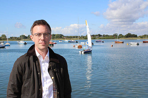 Ben Dempsey in front of boats on the water at Bosham