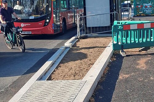 A street with a bus stop, bike lane under construction