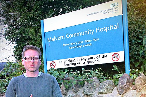Cllr Dan Boatright-Greene next the Malvern Hills NHS sign