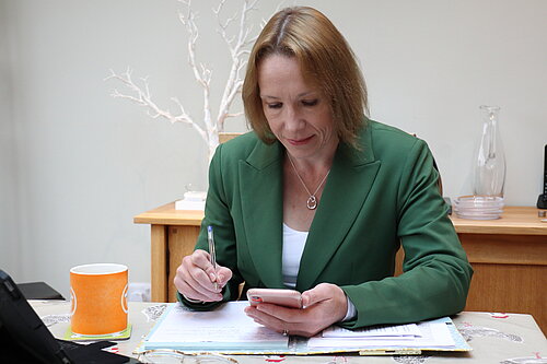 Helen Morgan MP at desk using mobile phone