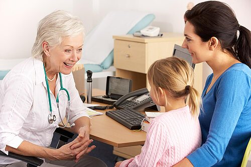 A mother holding a child whilst speaking to a GP
