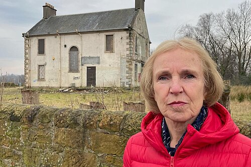 Susan Murray looking serious in a red jacket