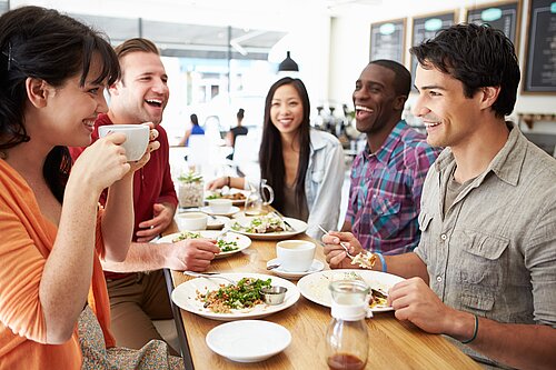 Group of young people sitting in a cafe eating.