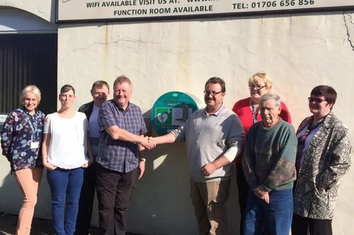 Lisa Kimpton (RMBC), Emma Lees, Andy Lees (Club Steward) Steve Lowe (Chairman of the Club), Councillor Irene Davidson, Club Stalwart Vic and Councillor Janet Emsley launch the defibrillator outside Milnrow Worker's Club
