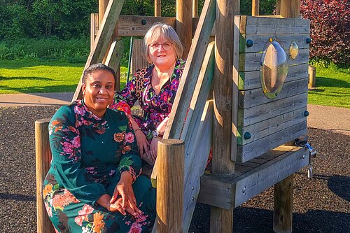 Chika Akinwale and Lorna Dupre sitting on equipment at a childrens playpark