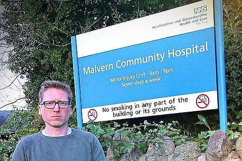 Dan Boatright-PPC looking angry next to Malvern Community Hospital Sign