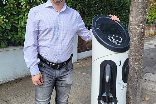 Cllr Gary Malcolm stood next to an EV charging station.