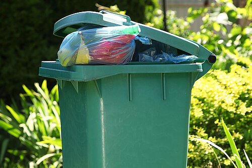 A wheelie bin overflowing with rubbish.