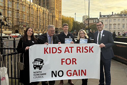 Tom Gordon and activists with a large banner reading "kids at risk for no gain" outside the Houses of Parliament
