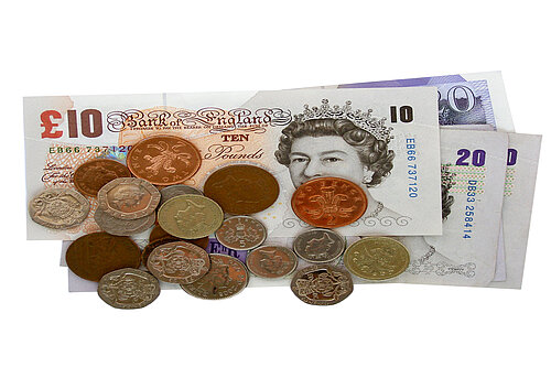 A pile of pound coins on top of notes.