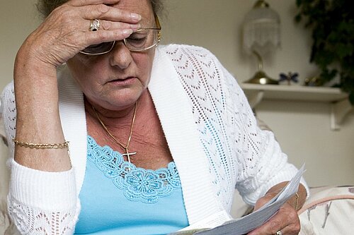 Woman looking concerned while reading a piece of paper