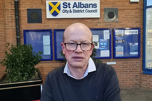 Councillor Paul de Kort is standing in front of the St Albans District council building.